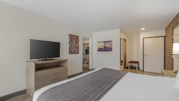Una habitación de hotel moderna con una cama grande, un televisor de pantalla plana, un escritorio y una silla.