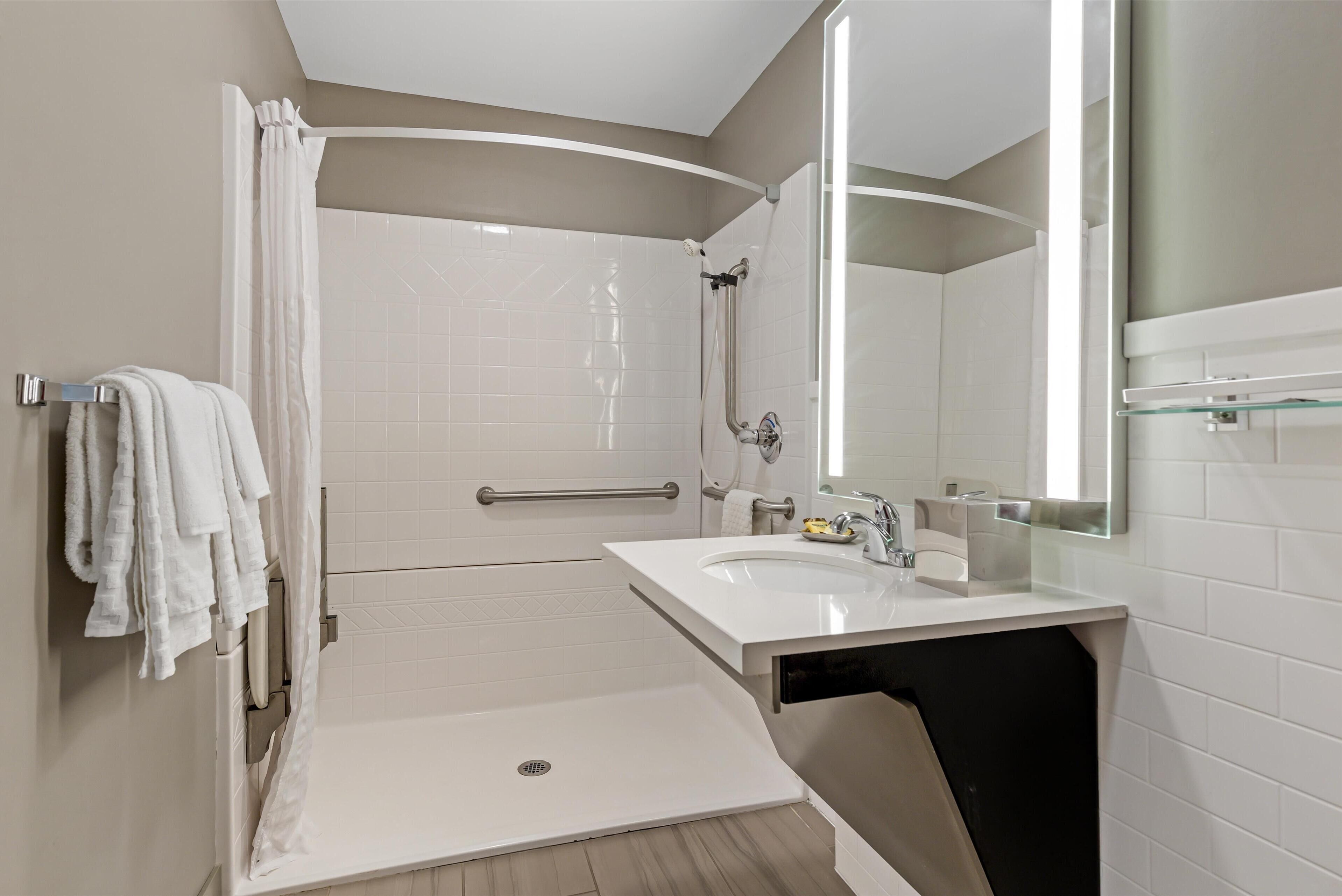A modern bathroom with a walk-in shower, a sink, and a large mirror.