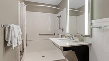 A modern bathroom with a walk-in shower, a sink, and a large mirror.