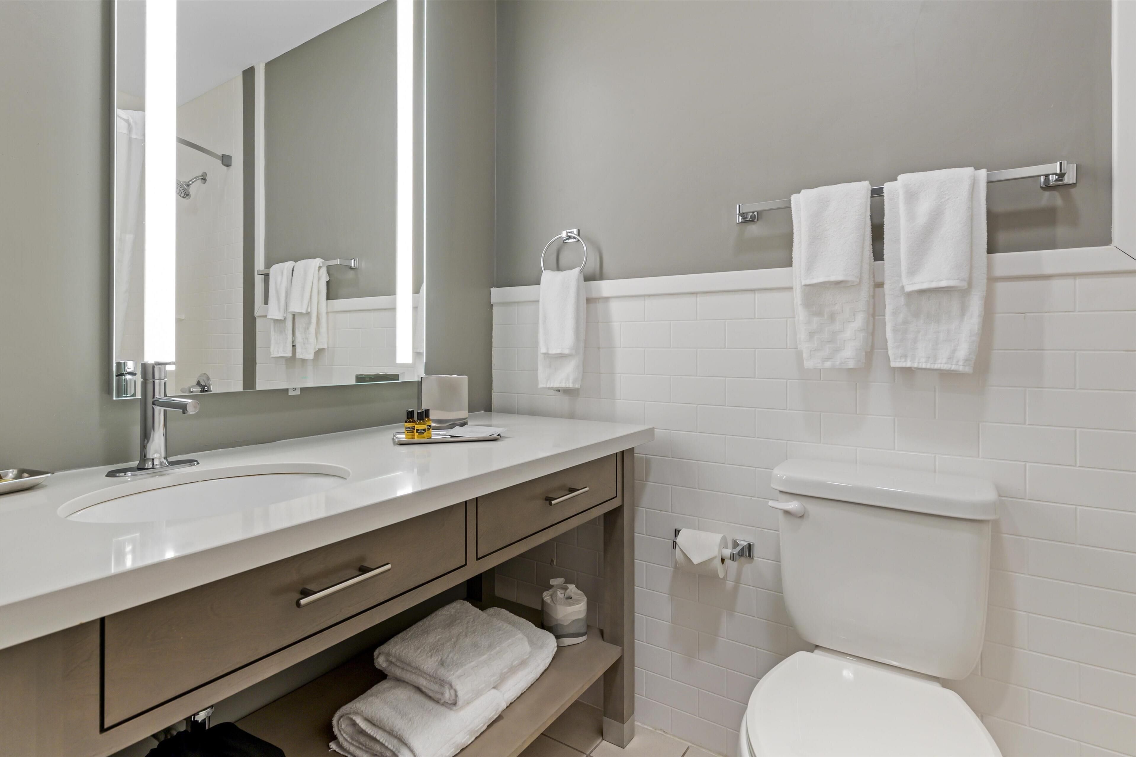 A modern bathroom with two sinks, a toilet, and a towel rack.