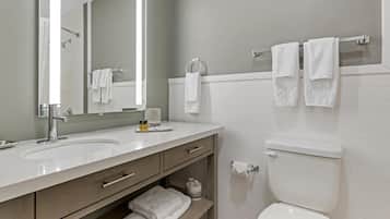 A modern bathroom with two sinks, a toilet, and a towel rack.