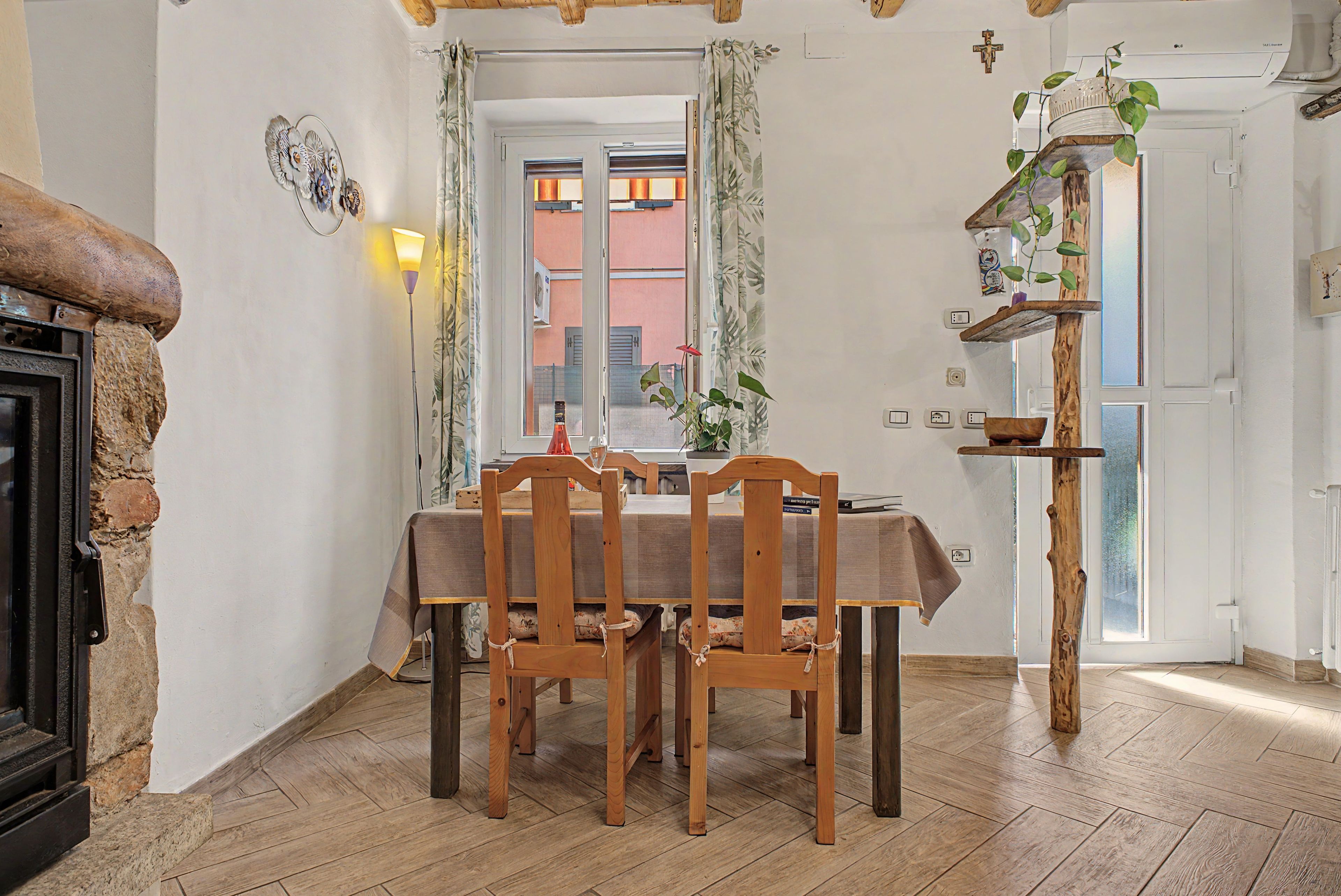 Ein Essbereich mit einem Holztisch, Stühlen, einer Chandelieber und einer Pflanze auf einem Holzregal.