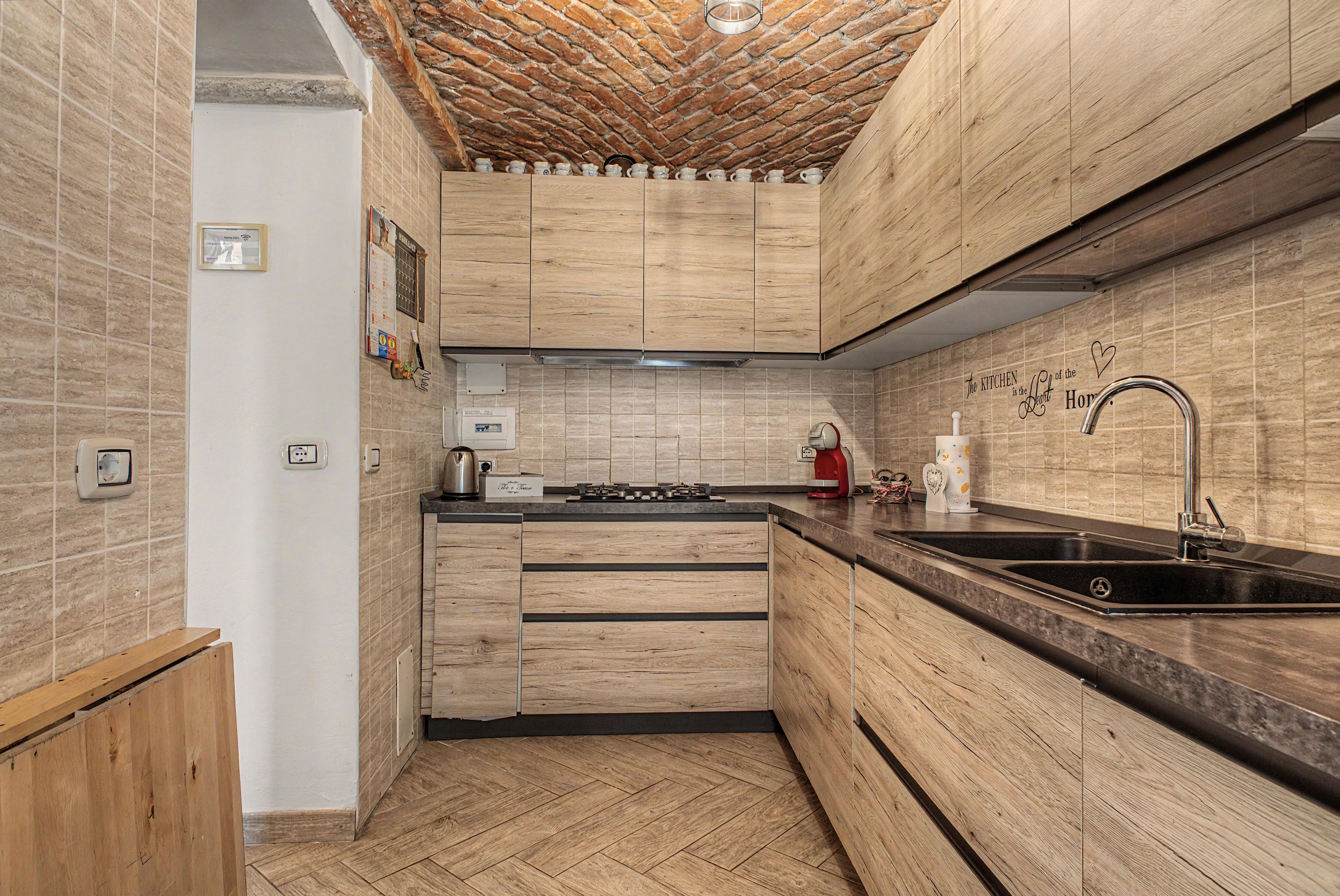 Eine moderne Küche mit Holzschränken, einer schwarzen Arbeitsplatte und einem Edelstahl-Spülbecken.