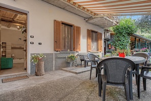 Ein Patio im Freien mit Tisch, Stühlen, einer Holztür und einem Blumentopf.