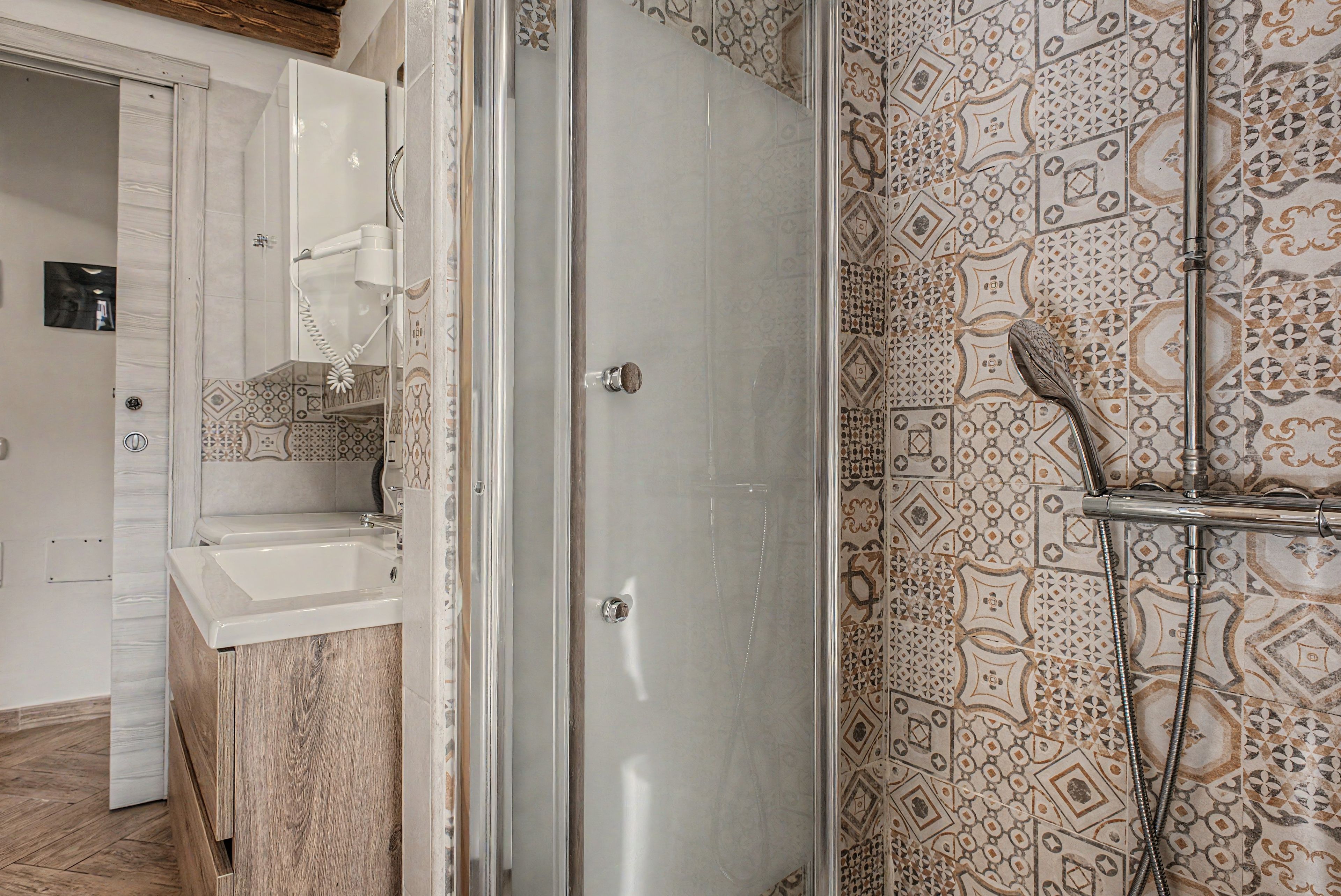 Une salle de bain avec une douche, un lavabo et des carreaux décorés.