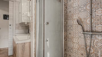 Une salle de bain avec une douche, un lavabo et des carreaux décorés.