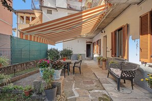 Une cour dotée d’un espace de repos abrité, de plantes en pot et offrant une vue sur la rue.