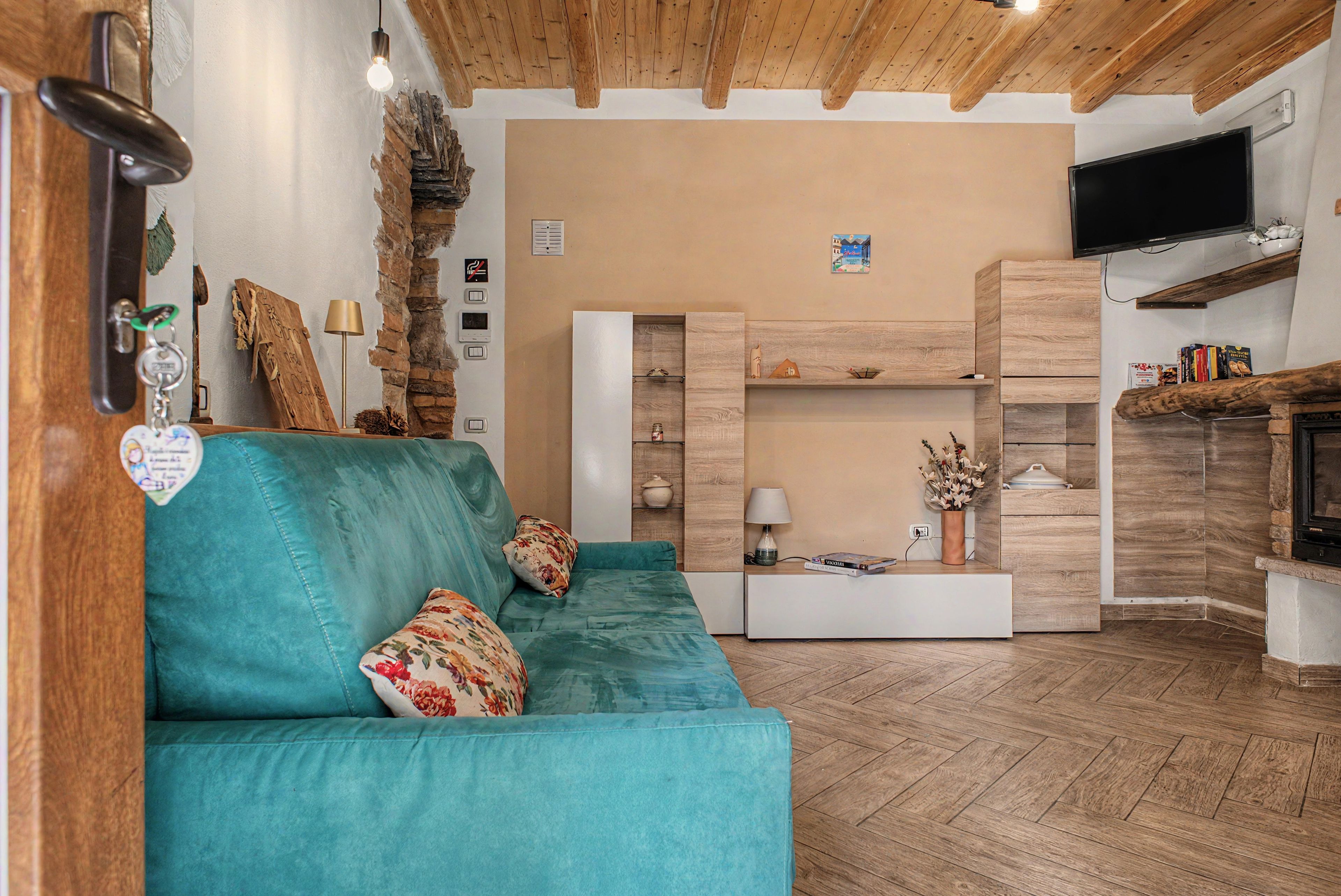 Un salon chaleureux avec un canapé de couleur turquoise, des étagères en bois, un téléviseur à écran plat et une cheminée.