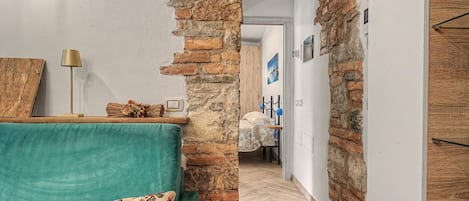 A room with a green sofa, a brick wall, and a wooden door.