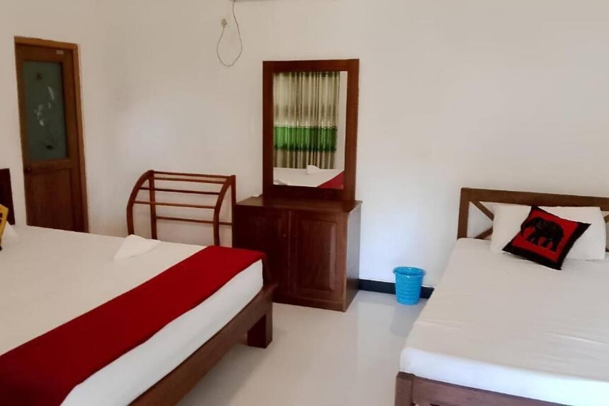 A hotel room with two beds, a wooden dresser, a chair, and a mirror.