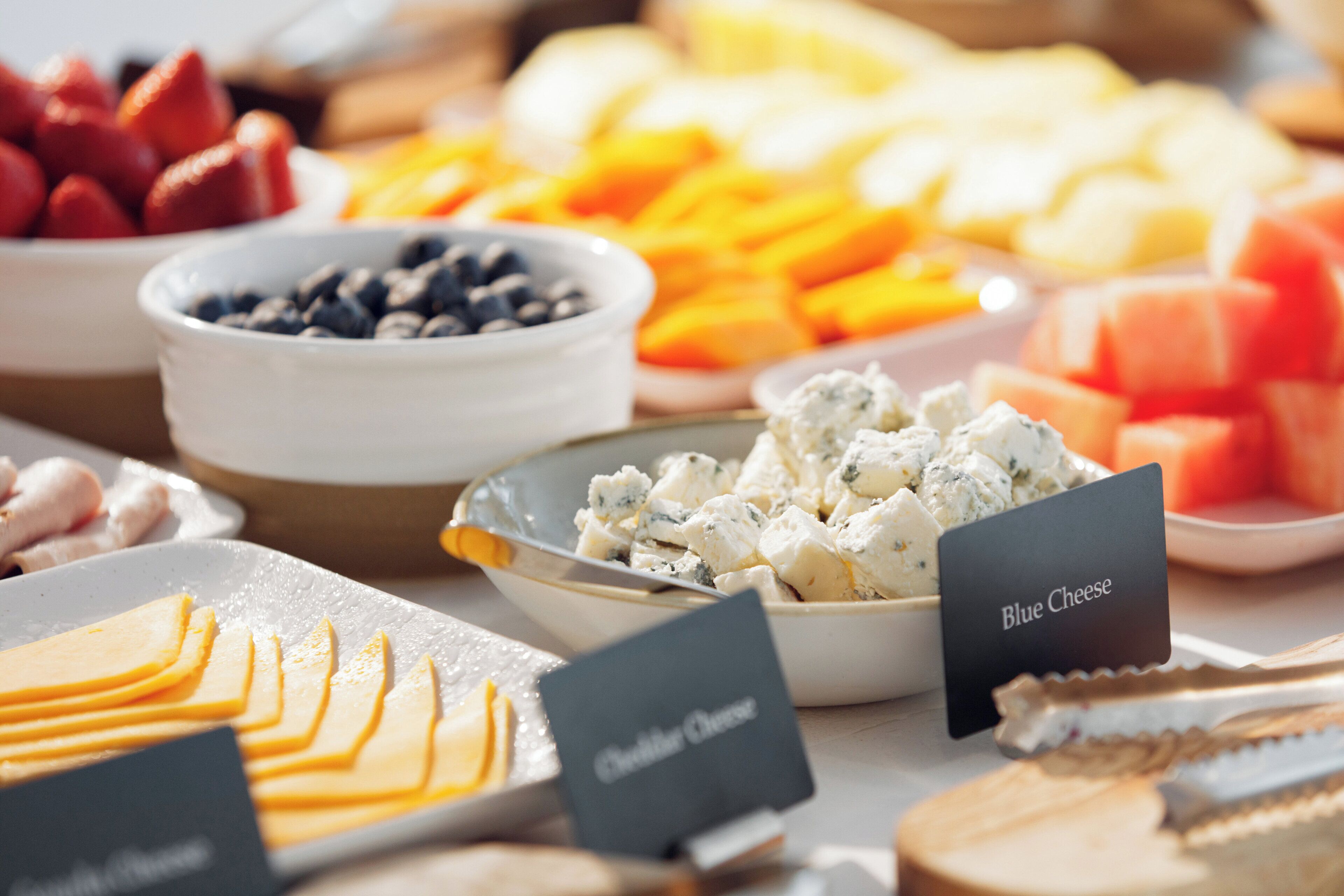 A variety of cheeses and fruits on a buffet table.
