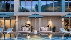 A modern pool area with lounge chairs and umbrellas, a seating area with cushions, and potted plants. - Hotel Indigo Turks Caicos Grace Bay by IHG (Providenciales)