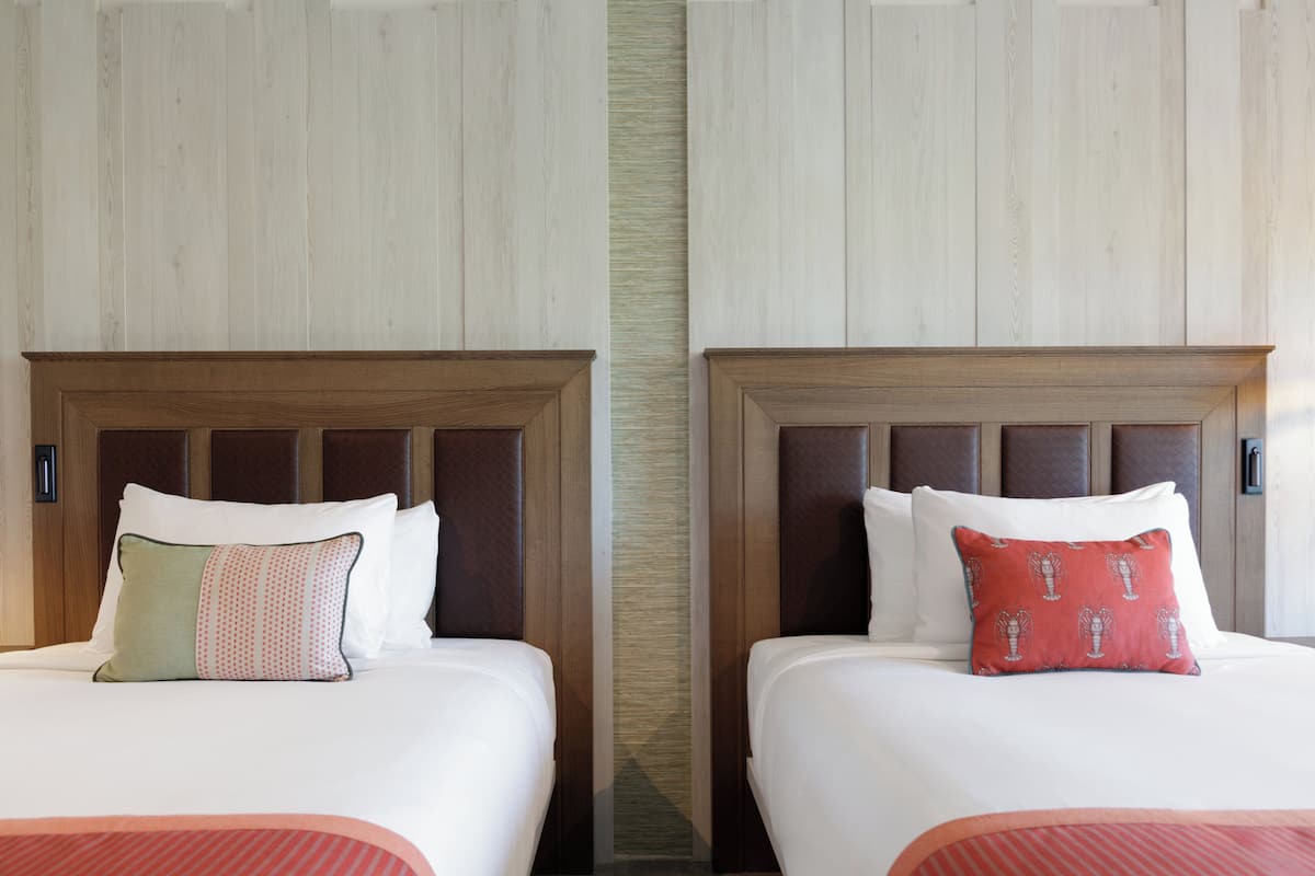 Two adjacent beds with wooden headboards, white bedding, and patterned pillows.