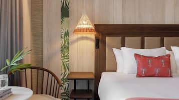 A hotel room with a bed, a bedside table, a chair, a small table, and a hanging light fixture.