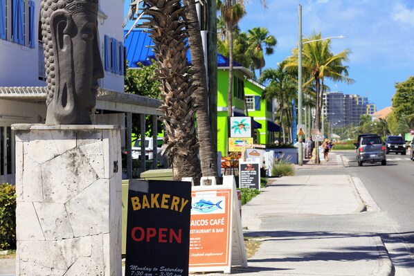 A street with a bakery sign, a statue, and a building with a blue roof.