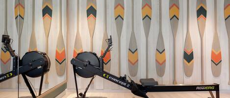 A rowing machine in a room with a mirrored wall and decorative paddles.