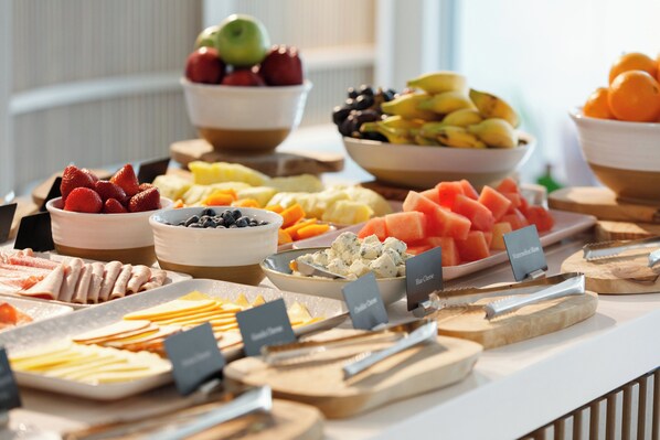 A buffet with various food items including fruits, cheeses, and meats.