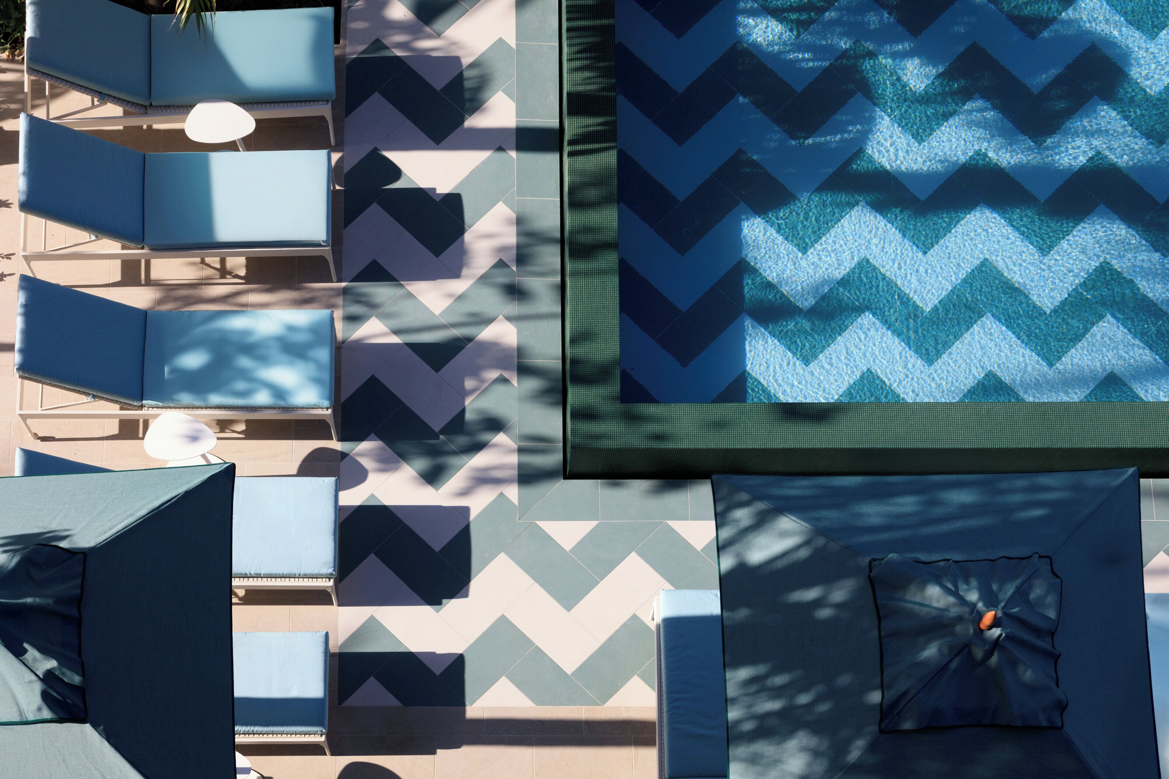 A modern outdoor seating area with multiple lounge chairs and a patterned floor.