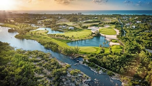 A golf course with a lake, surrounded by greenery and buildings. - Hotel Indigo Turks Caicos Grace Bay by IHG (Providenciales)