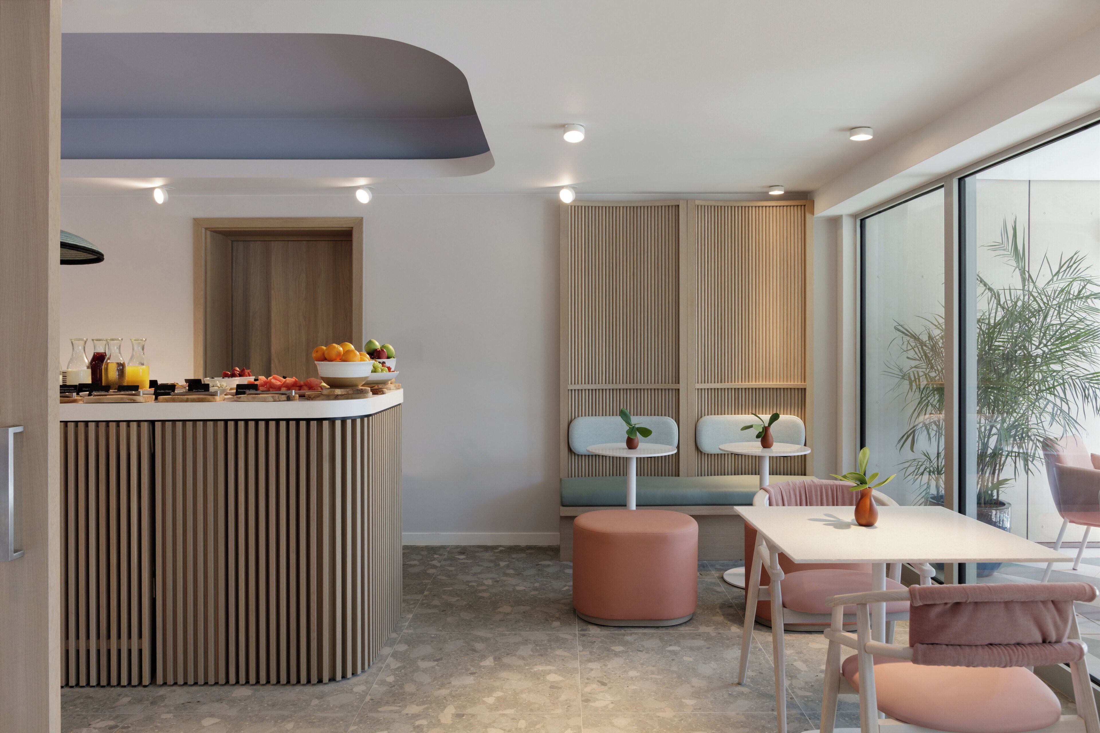 A modern kitchen with a central island, seating area with a table and chairs, and a large window providing a view.