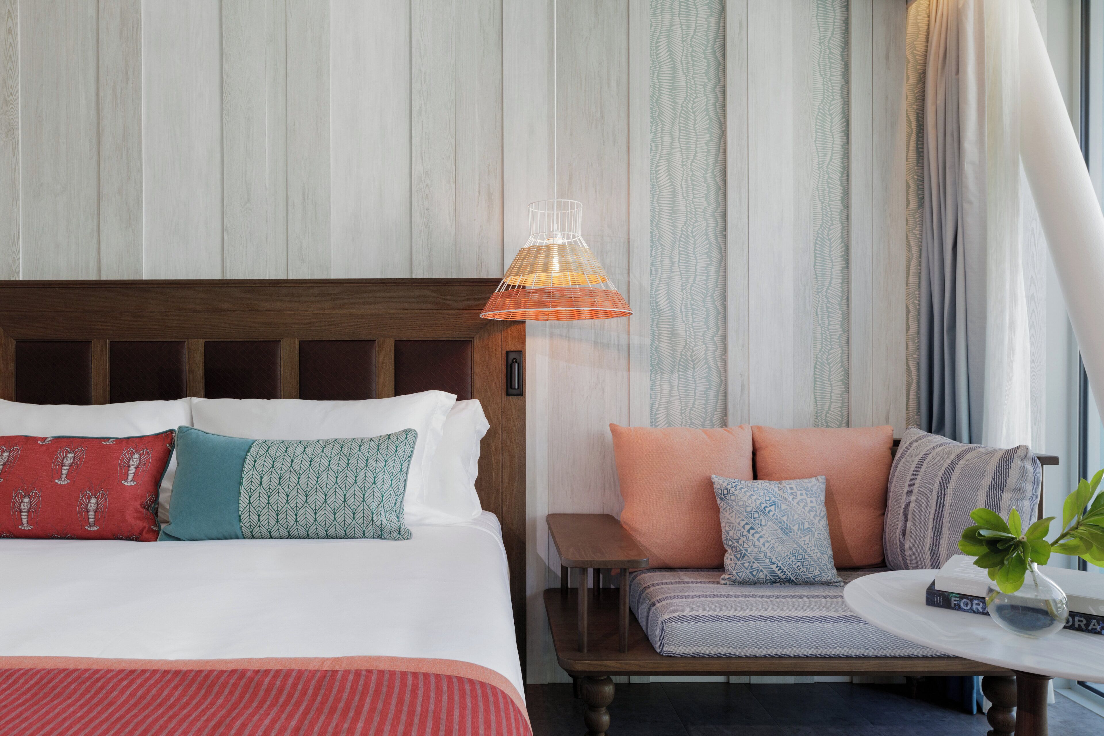Una habitación de hotel con cama, sofá, una mesita y una lámpara colgante.