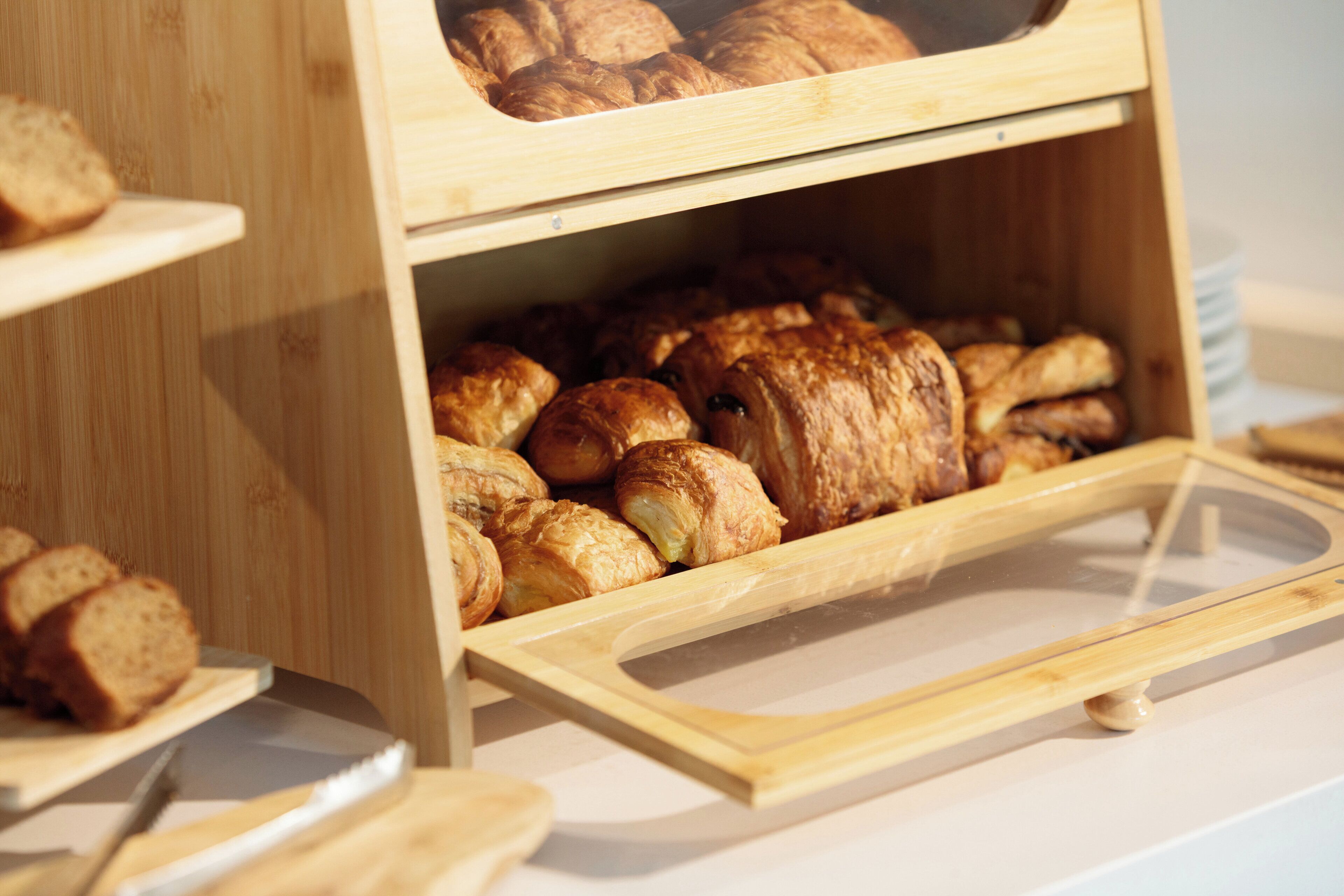 A wooden display case with baked goods, including bread and pastries.
