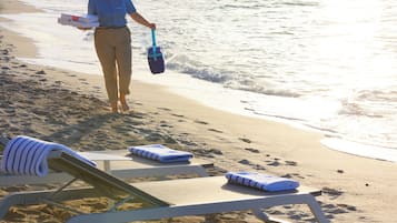 Une plage avec des chaises longues et une personne qui porte un sac et une boîte.