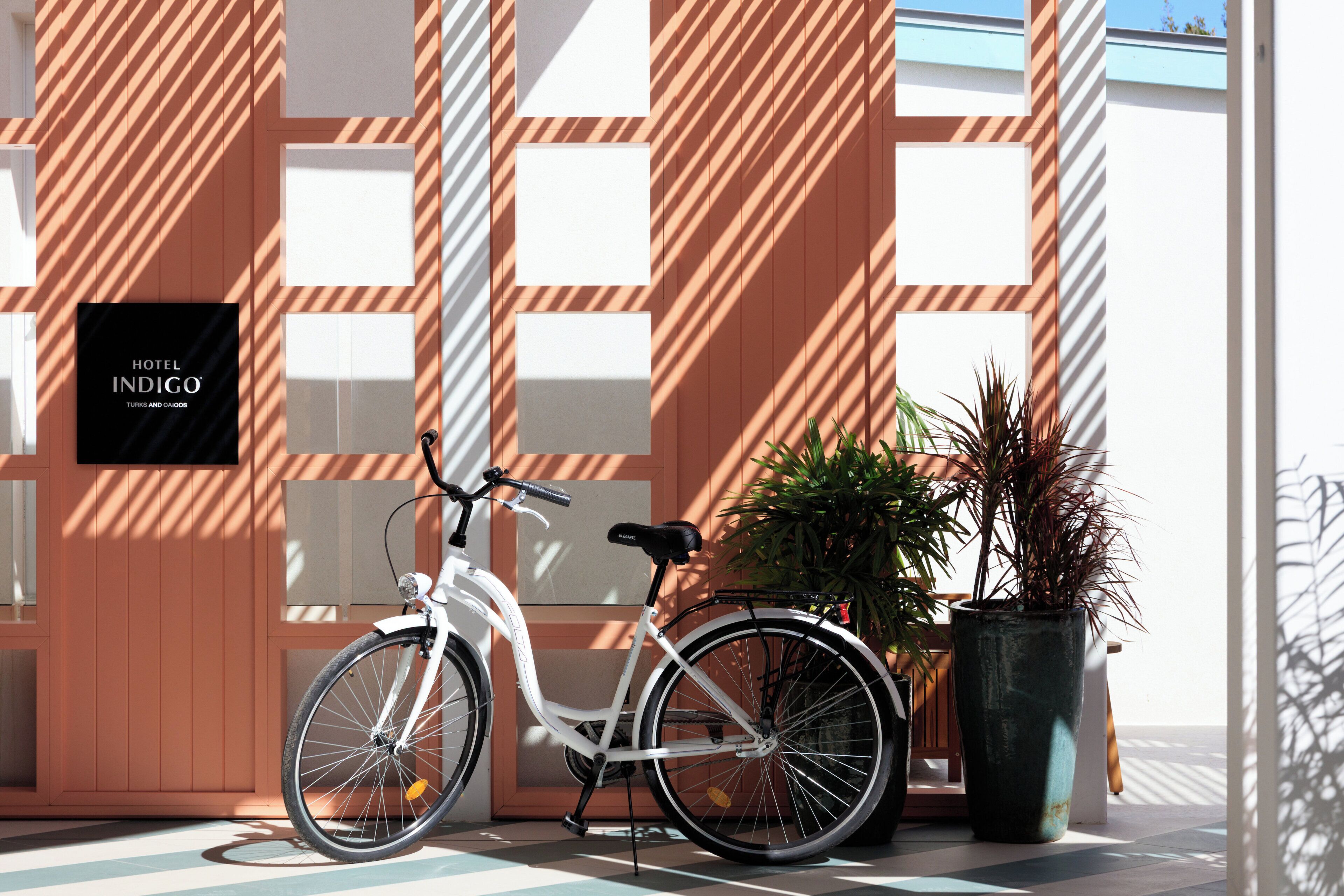 En hvid cykel parkeret foran en bygning med et skilt, der viser 'HOTEL INDIGO'.