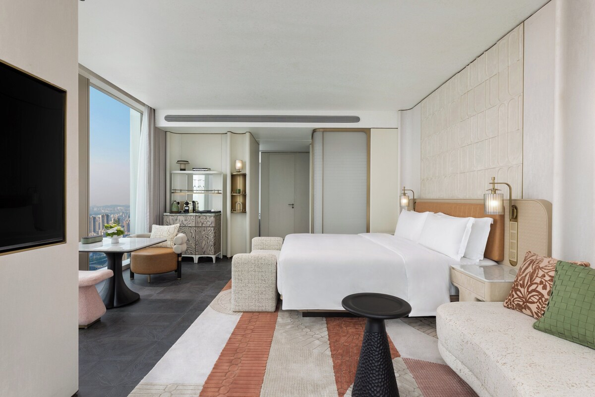 Una habitación de hotel moderna con una cama grande, un sofá, una mesa de comedor y un televisor.