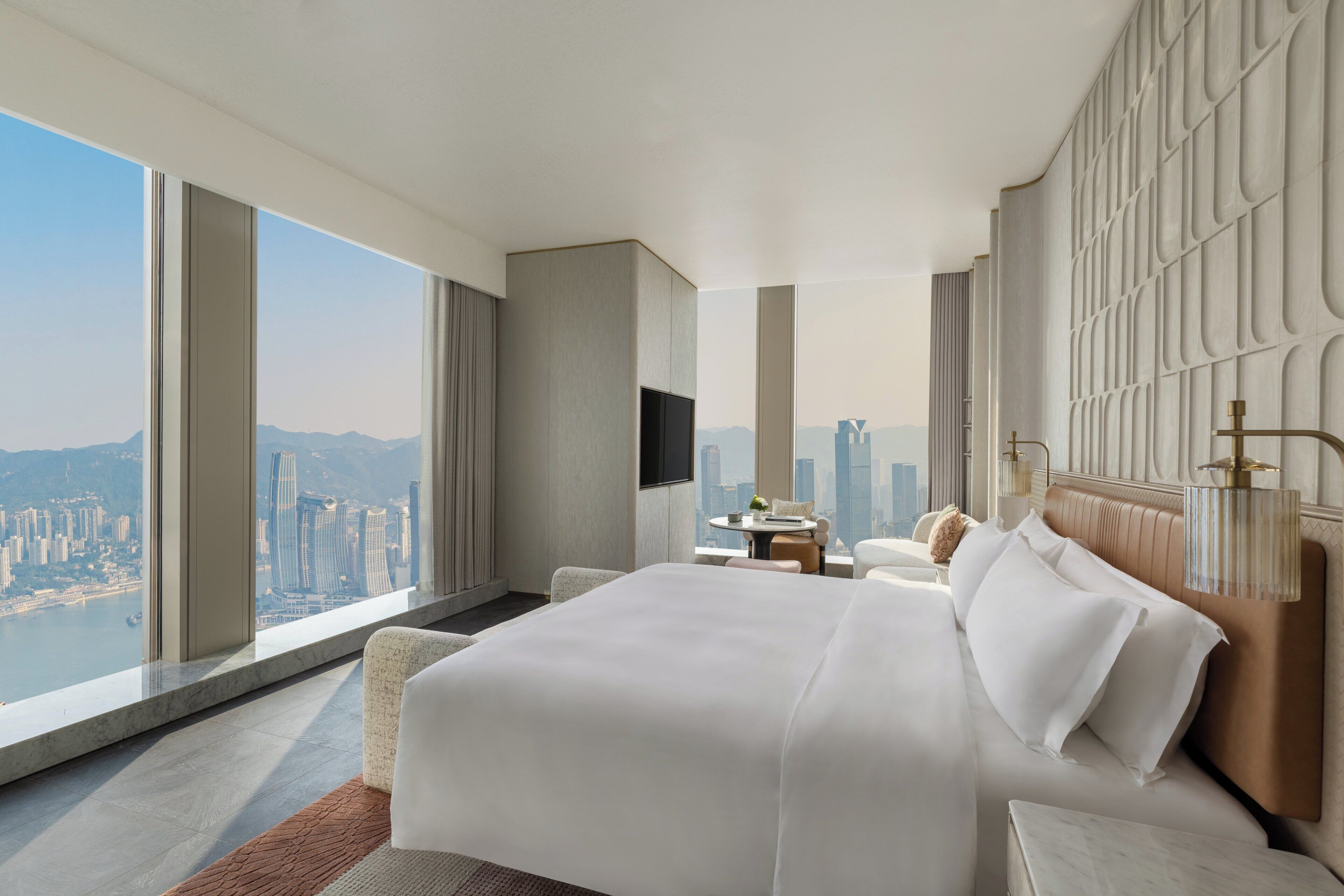 A modern hotel room with a large bed, a city view, and a minimalist design.