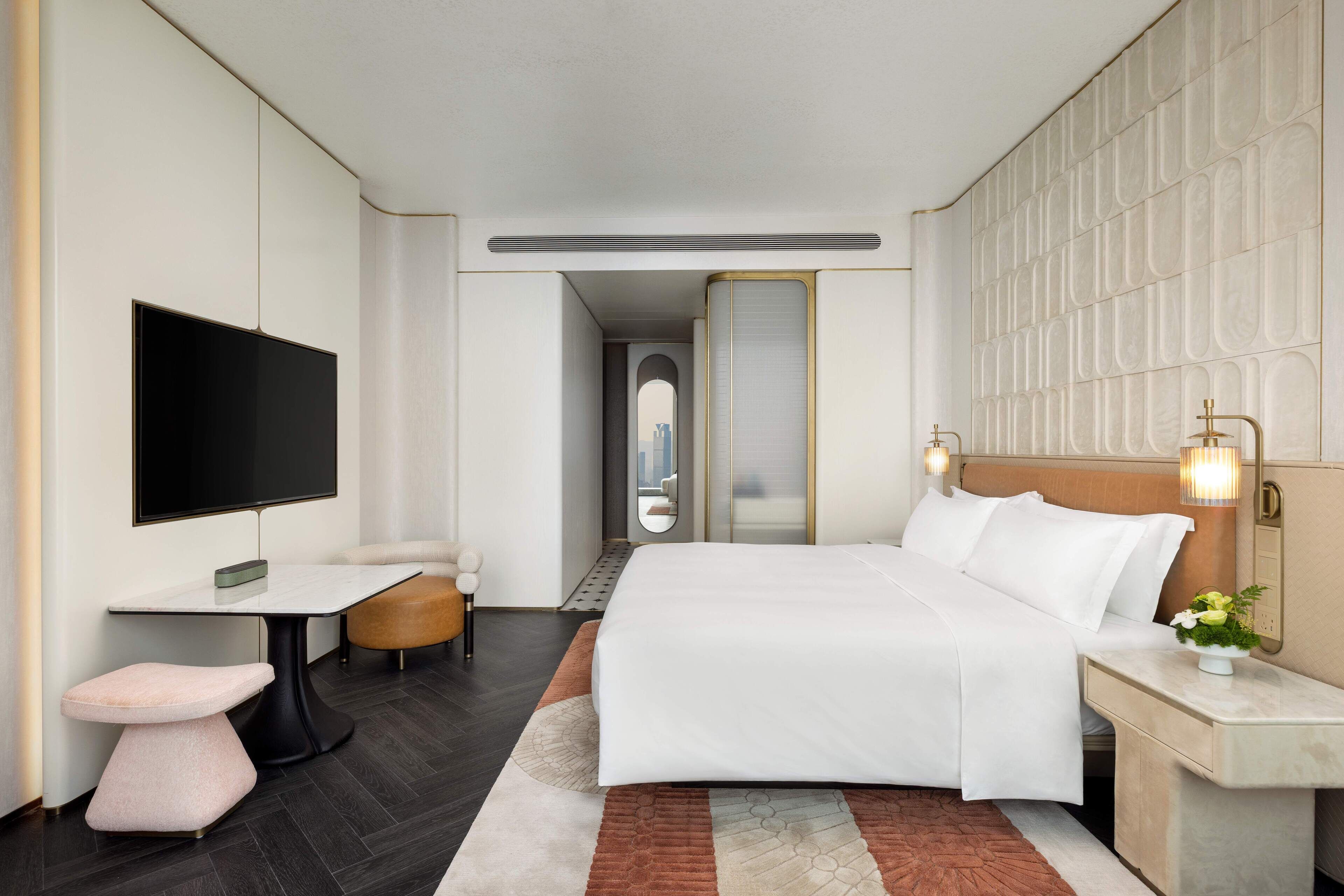 Una habitación de hotel moderna con una cama grande, un televisor de pantalla plana, un escritorio y un área de descanso acogedora.