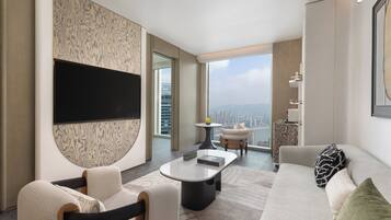 A modern living room with a flat-screen TV, a sofa, a coffee table, and a view of the cityscape.