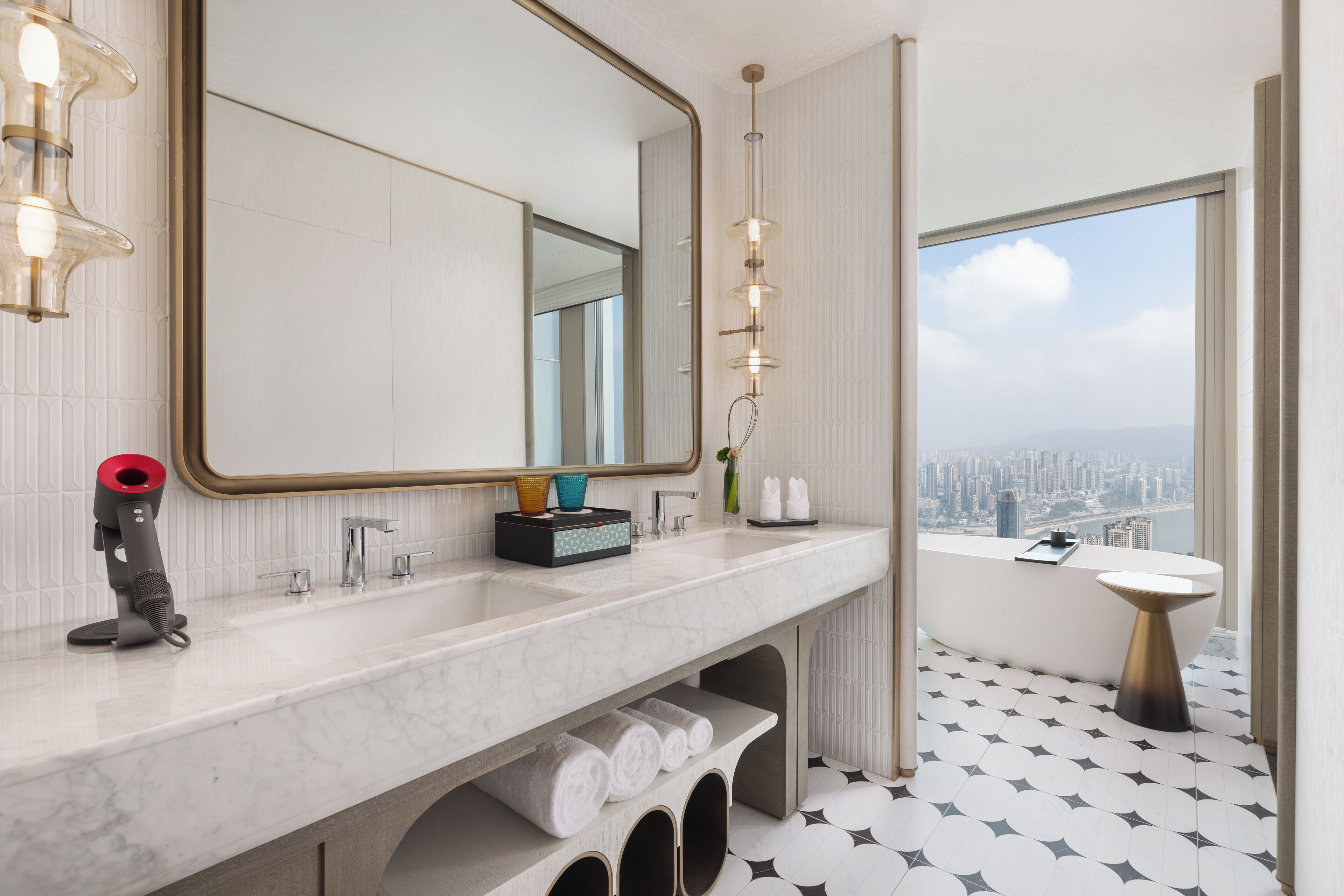 Un baño moderno con un espejo grande, una bañera y vistas a la ciudad.