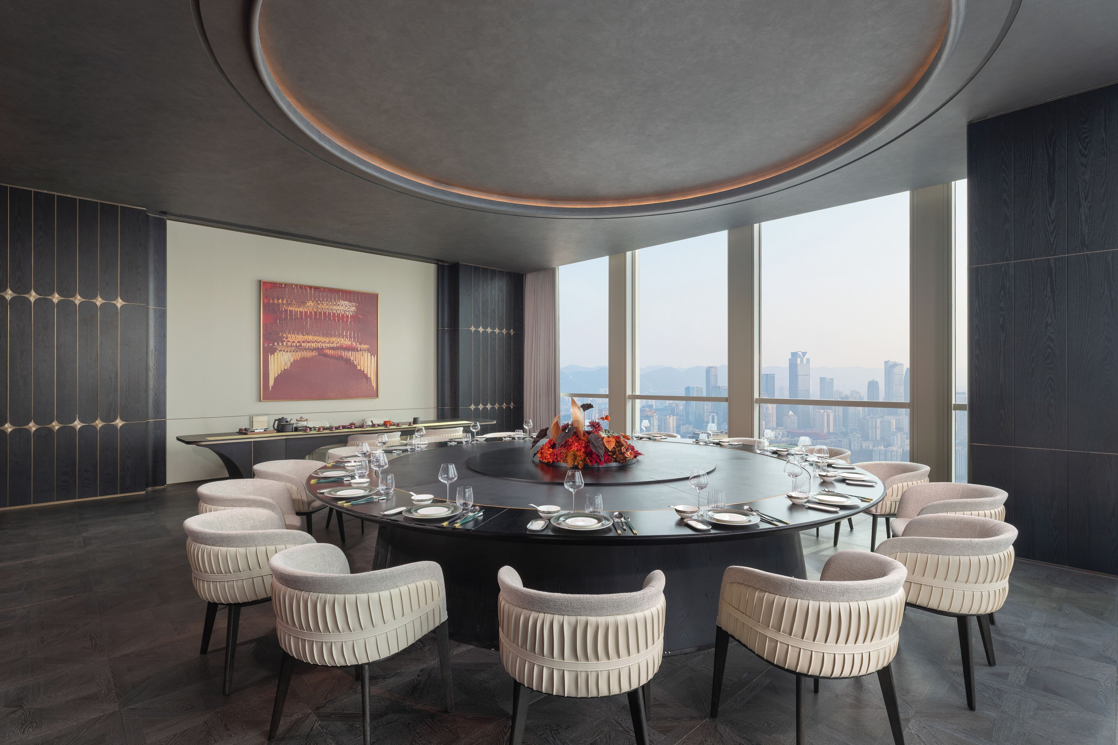A modern dining room with a round table, six chairs, and a city view.