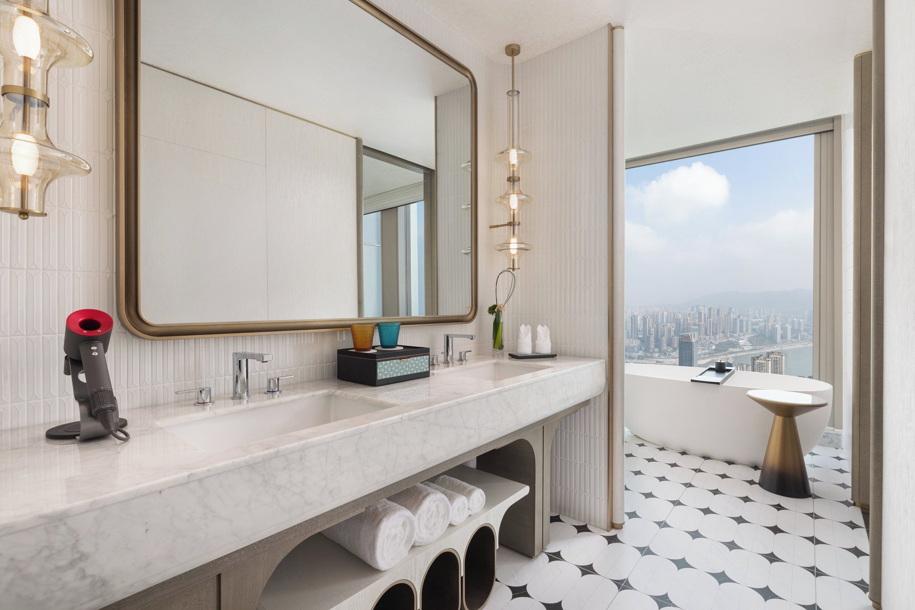 Une salle de bain moderne avec un grand miroir, une baignoire, un lavabo et une vue sur la ville.