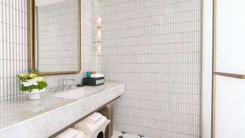 Une salle de bain moderne avec un lavabo en marbre, un grand miroir et un mur recouvert de carreaux disposés en motif quadrillé.