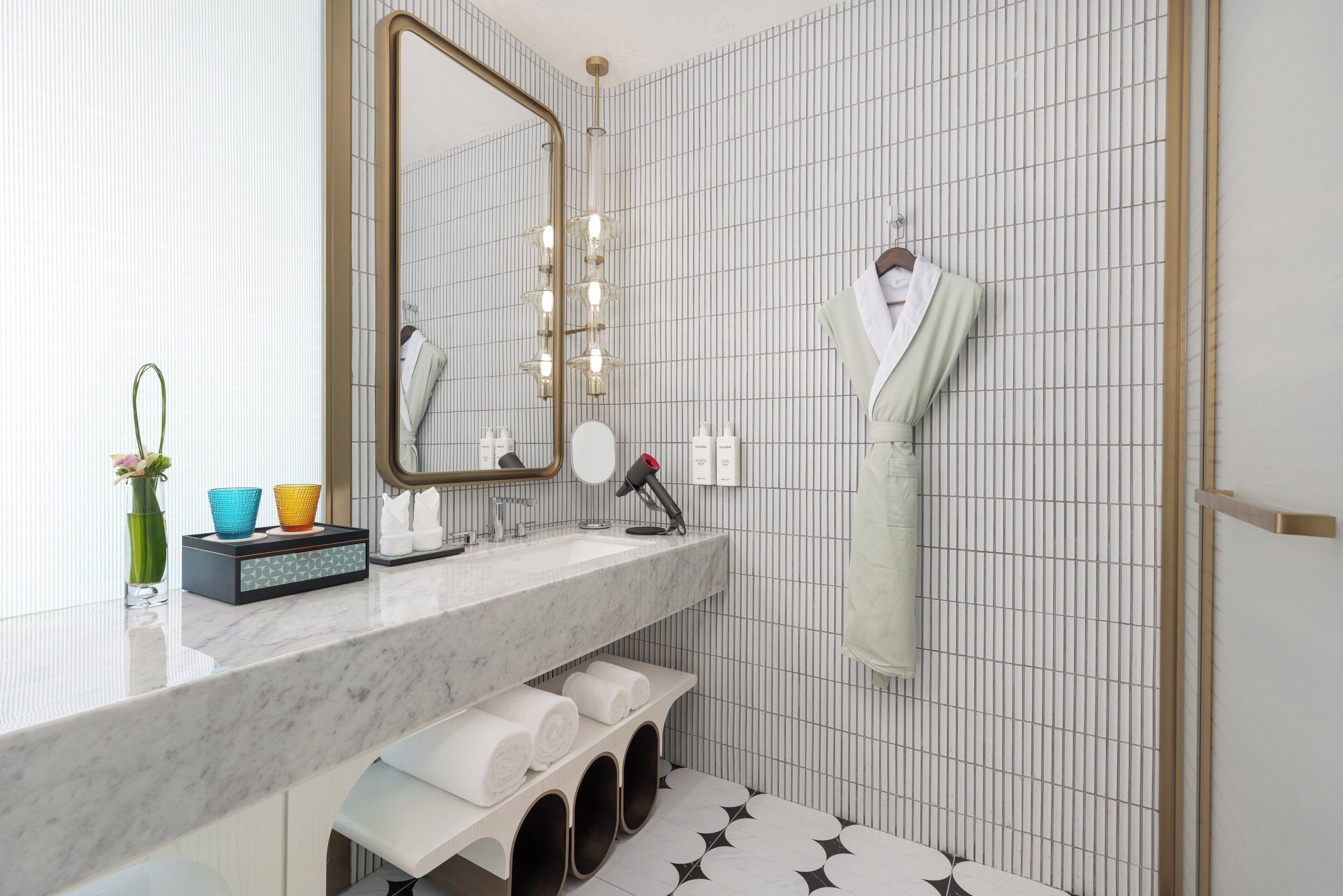 Un bagno moderno con lavabo in marmo, uno specchio grande e un portasciugamani.