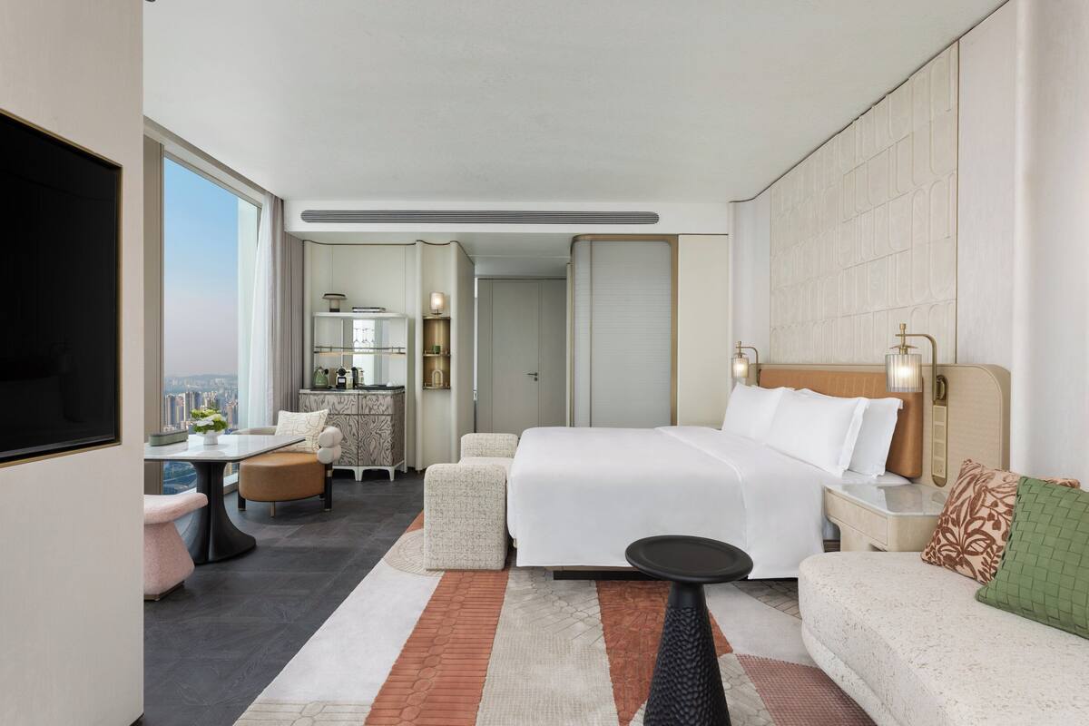 Una habitación de hotel moderna con una cama grande, un sofá, una mesa de comedor y un televisor.