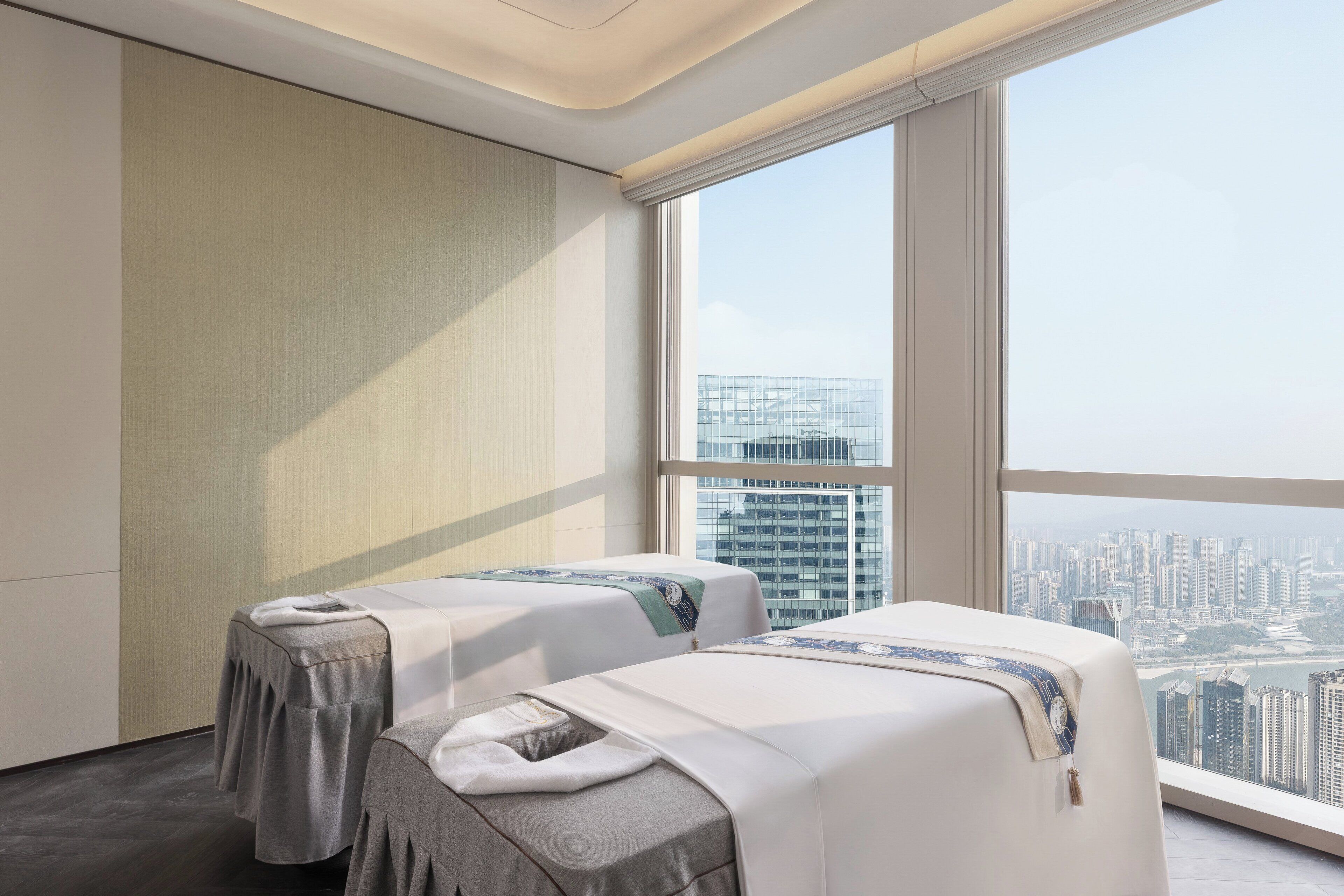 A hotel room with two beds, a large window with a city view, and a modern design.