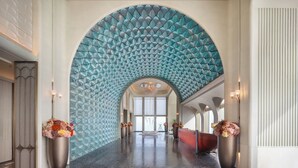 Un hall d’entrée spacieux avec un grand plafond en arc, un comptoir de réception et deux grands vases remplis de fleurs.