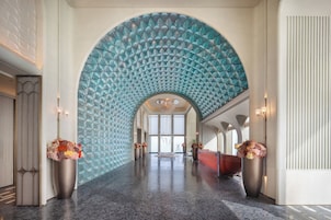 A spacious lobby with a large arched ceiling, a reception desk, and two large vases with flowers.