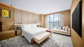 Ett modernt hotellrum med en stor säng, en soffa, ett skrivbord och utsikt över staden.