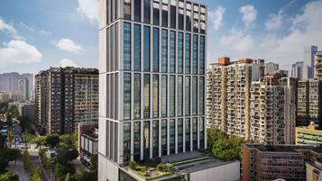 Un moderno edificio de gran altura con fachada de vidrio, rodeado de otros edificios residenciales.