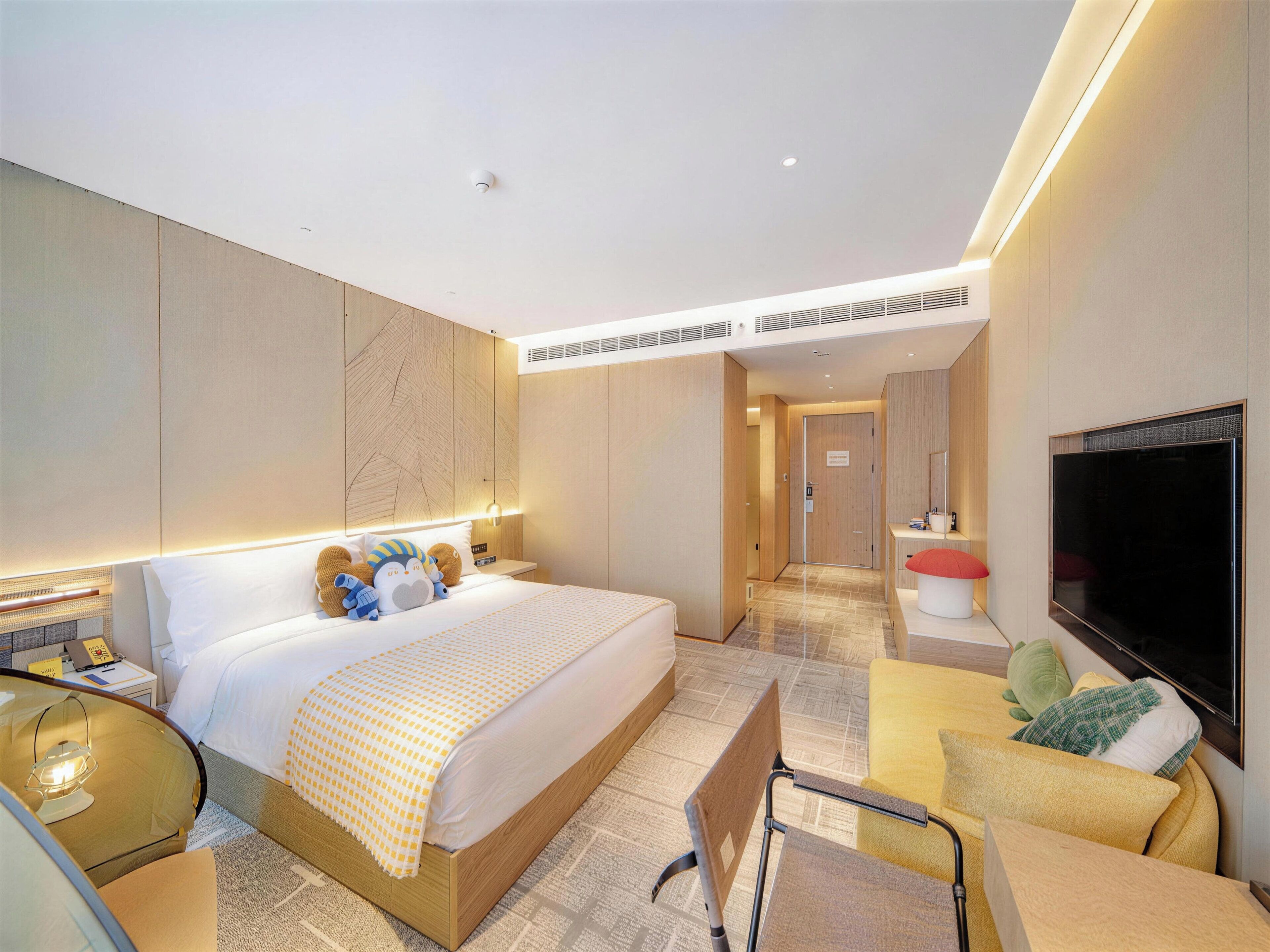 A modern hotel room with a large bed, a flat-screen TV, a desk, and a chair.