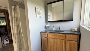 A bathroom with a wooden vanity, a large mirror, and a shower curtain. - Charming 3-bedroom farmhouse in Astoria (Astoria)
