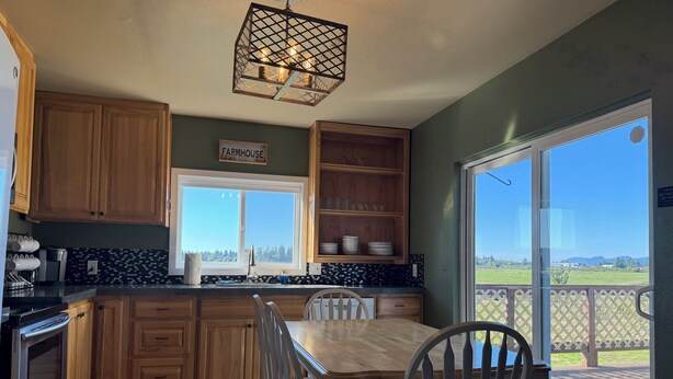 A kitchen with wooden cabinets, a farmhouse sign, a large window, and a dining table with chairs. - Charming 3-bedroom farmhouse in Astoria (Astoria)