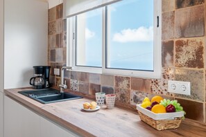 A kitchen with a sink, coffee maker, and a fruit basket on the counter. - Simone haystack by Homie (Porto Moniz)