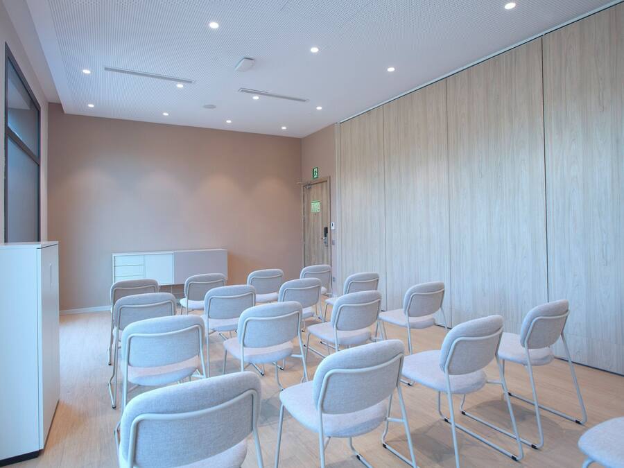 Un salón de conferencias con filas de sillas, una pizarra y un panel de pared de madera.