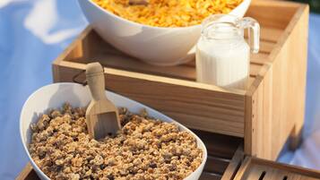 A wooden tray with two bowls of granola and a milk jug.