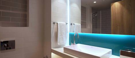 Un baño moderno con un lavamanos blanco, un espejo y una pared de acento azul.